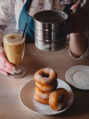 Pishki - Rus çörek. Kız toz pudra şekeri çörek üzerinde geleneksel kantinde bir arka plan üzerinde uzun bir şeffaf bardak kakao içmeye kız. Dikey fotoğraf