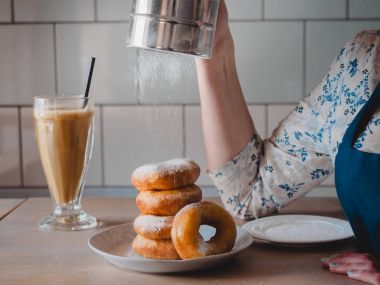 Pishki - Rus çörek. Kız toz pudra şekeri çörek üzerinde geleneksel kantinde bir arka plan üzerinde uzun bir şeffaf bardak kakao içmeye kız. Yatay fotoğraf
