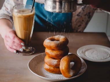 Pishki - Rus çörek. Kız toz pudra şekeri çörek üzerinde geleneksel kantinde bir arka plan üzerinde uzun bir şeffaf bardak kakao içmeye kız. Yatay fotoğraf