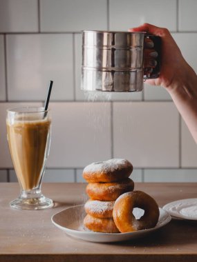 Pishki - Rus çörek. Kız toz pudra şekeri çörek üzerinde geleneksel kantinde bir arka plan üzerinde uzun bir şeffaf bardak kakao içmeye kız. Dikey fotoğraf