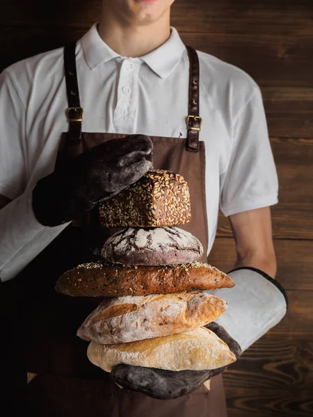 Variety of freshly baked breads in a young bakers hands — Stock Photo, Image