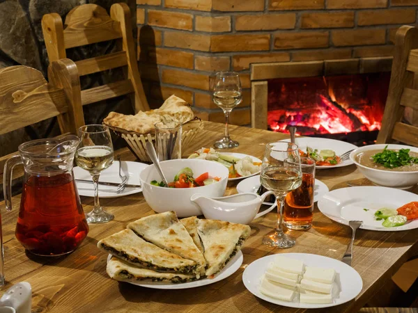 格鲁吉亚餐桌 壁炉的背景 餐桌上有传统食物 Lobio 炖豆腐 水平照片 — 图库照片