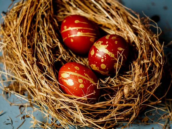 Beautiful Easter red and gold eggs on hay. Three eggs on hay. horizontal photo