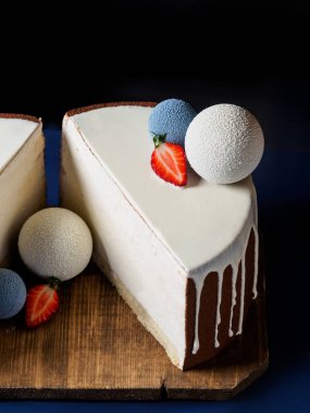 Beyaz çikolata kadife ile kaplı ve çikolata küre ile dekore kek yakın çekim Mus şaşırtıcı. Kesilmiş yarım, dikey fotoğraf, koyu arka plan