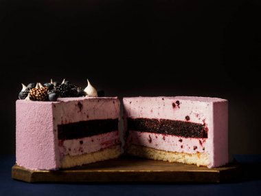 lezzetli mousse kek Close-Up pembe sır ile kaplı ve koyu arka plan üzerinde çikolata şekerleme ile dekore edilmiş