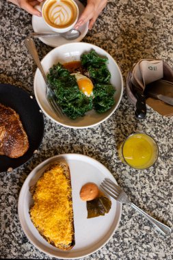 Kahvaltı masası: yukarıdaki mermer masada yumurtalı sandviç, meyve suyu ve salata.