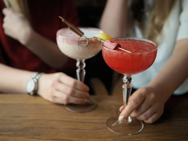 Kristal bardakta kırmızı ve beyaz kokteyller tutan kızlar
