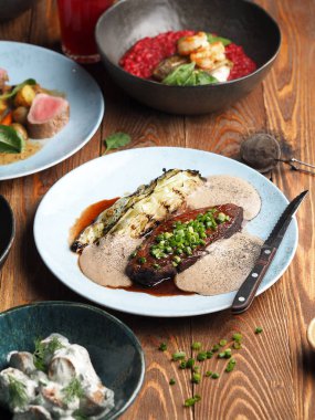 Ahşap masada ızgara lahana ve kremalı sos ile nefis biftek.