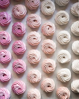 Pastel renkte krem şantili büyük grup pastalarının beyazdan pembeye fırınlama kağıdının üstünde görünümü