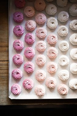 Pastel renkte krem şantili büyük grup pastalarının beyazdan pembeye fırınlama kağıdının üstünde görünümü