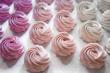 Pastel renkte krem şantili büyük grup pastalarının beyazdan pembeye fırınlama kağıdının üstünde görünümü