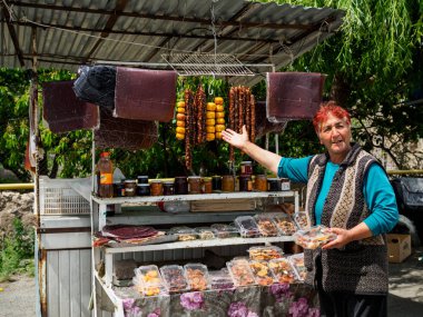 Ermenistan, Mayıs 2019. Kadın Ermeni tatlıları sunuyor: Sudjuk (Churchkhela) ve markette doldurulmuş şeftali. Kafkasya 'nın geleneksel yemekleri  
