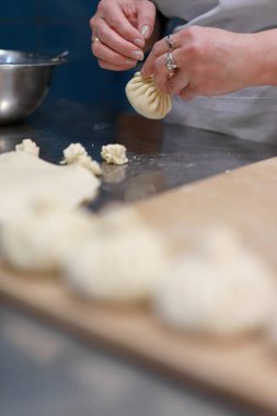 Georgian cuisine: woman making khinkali. Female hands holding dough. Vertical