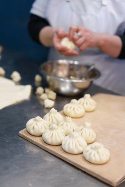 Georgian cuisine: woman making khinkali. Female hands holding dough. Vertical