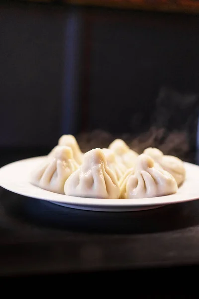 Georgian cuisine: hot boiled khinkali on a plate, black background