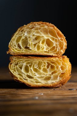 Mükemmel kruvasan kesimi. Ahşap bir masada sade kruvasan kesiği, siyah arka plan.