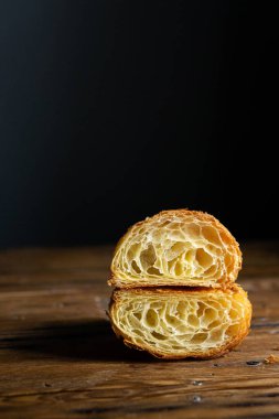 Mükemmel kruvasan kesimi. Ahşap bir masada sade kruvasan kesiği, siyah arka plan.