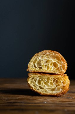 Mükemmel kruvasan kesimi. Ahşap bir masada sade kruvasan kesiği, siyah arka plan.