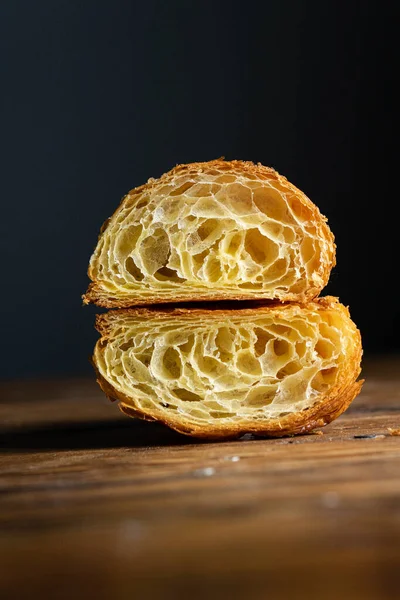 Mükemmel kruvasan kesimi. Ahşap bir masada sade kruvasan kesiği, siyah arka plan.