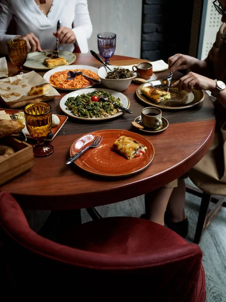 Traditional Armenian breakfast in a restaurant: varieties of scrambled eggs, breads, coffee. Girls having breakfast in Yerevan