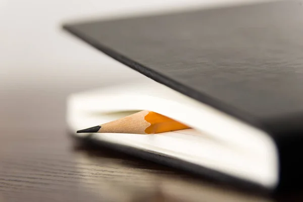 Pencil on the pages of an closed notebook for records — Stock Photo, Image