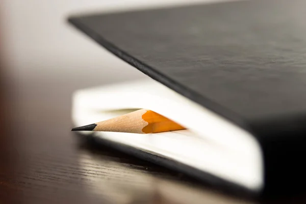 Pencil on the pages of an closed notebook for records — Stock Photo, Image