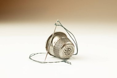 Metal yüksük ve iğne ile beyaz iş parçacığında