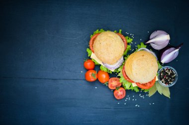 Peynir, et, domates ve soğan ve otlar ile hamburger. Ahşap arka plan üzerinde. Üstten Görünüm. Boş alan.