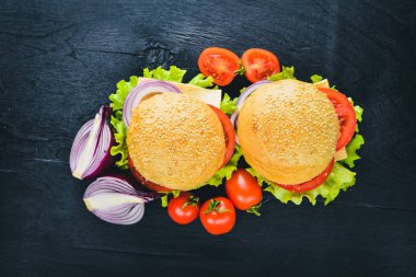Peynir, et, domates ve soğan ve otlar ile hamburger. Ahşap arka plan üzerinde. Üstten Görünüm. Boş alan.