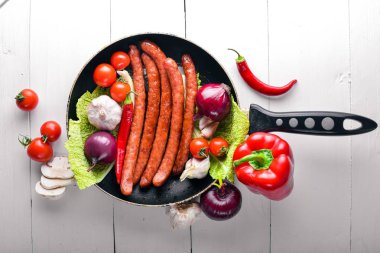 Taze sebze ile bir tavada ızgara sosis. Siyah yüzeyi ahşap. Üstten Görünüm.