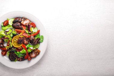 Salata taze salatalık, domates ve yeşillik bir plaka ahşap tahta üzerinde ızgara et ile. Üstten Görünüm. Boş alan.