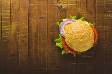 Peynir, et, domates ve soğan ve otlar ile hamburger. Ahşap arka plan üzerinde. Üstten Görünüm. Boş alan.