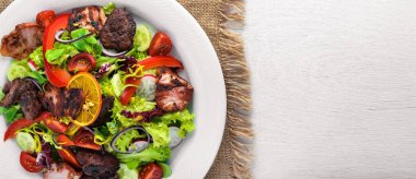 Salata taze salatalık, domates ve yeşillik bir plaka ahşap tahta üzerinde ızgara et ile. Üstten Görünüm. Boş alan.