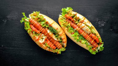 Sosis ızgara sosis, hardal ve ketçap, soğan ve Yeşiller ahşap arka plan üzerinde. Üstten Görünüm. Boş alan.