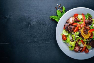 Salata taze salatalık, domates ve yeşillik bir plaka ahşap tahta üzerinde ızgara et ile. Üstten Görünüm. Boş alan.