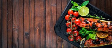 Bruschetta domates, zeytin, otlar ve parmesan peyniri ekmeğin. Soğuk aperatifler. İtalyan mutfağı. Ahşap arka plan üzerinde.