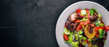 Salata taze salatalık, domates ve yeşillik bir plaka ahşap tahta üzerinde ızgara et ile. Üstten Görünüm. Boş alan.