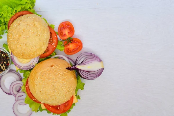 Hamburguesa con queso, carne, tomates y cebollas y hierbas. Sobre fondo de madera. Vista superior. Espacio libre . — Foto de Stock