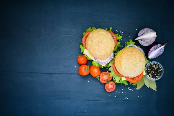 Peynir, et, domates ve soğan ve otlar ile hamburger. Ahşap arka plan üzerinde. Üstten Görünüm. Boş alan.