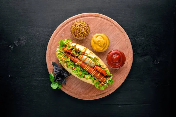 Hot dog con hierbas y especias, mostaza y ketchup. Sobre fondo de madera. Espacio de visualización superior . — Foto de Stock