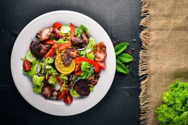 Salata taze salatalık, domates ve yeşillik bir plaka ahşap tahta üzerinde ızgara et ile. Üstten Görünüm. Boş alan.