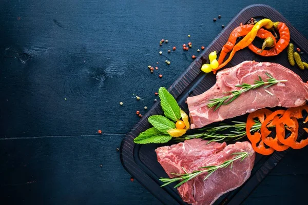 Steak nyers hús és a fűszerek, fából készült táblán. Felülnézet. Szabad hely. — Stock Fotó