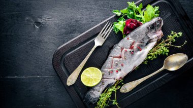 Balık alabalık aromatik otlar ve baharatlar ile. Ahşap arka plan üzerinde.