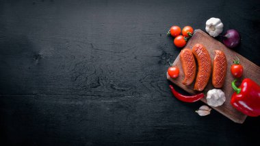 Taze sebze ile bir tavada ızgara sosis. Siyah yüzeyi ahşap. Üstten Görünüm.