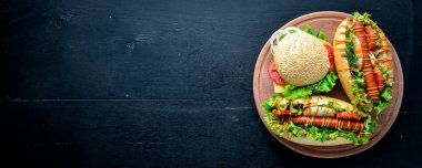 Sosisli sandviç ve hamburger ile peynir, et ve Yeşiller ahşap arka plan üzerinde. Üstten Görünüm. Boş alan.