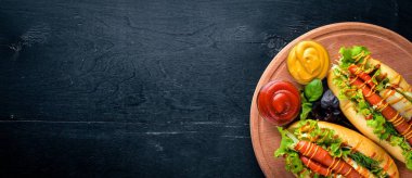 Sosis ızgara sosis, hardal ve ketçap, soğan ve Yeşiller ahşap arka plan üzerinde. Üstten Görünüm. Boş alan.