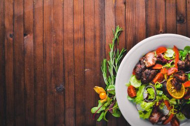 Salata taze salatalık, domates ve yeşillik bir plaka ahşap tahta üzerinde ızgara et ile. Üstten Görünüm. Boş alan.