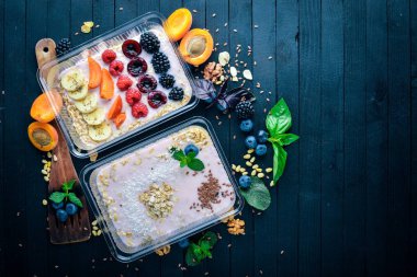 Yoğurt ve meyve ile yulaf gevreği. Sağlıklı bir diyet yemek. Öğle Yemeği boks. Siyah ahşap arka plan üzerinde. Üstten Görünüm. Metin için boş alan.