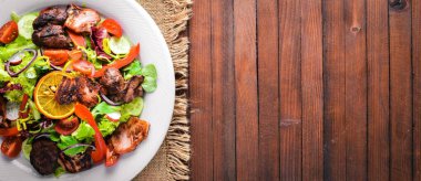 Salata taze salatalık, domates ve yeşillik bir plaka ahşap tahta üzerinde ızgara et ile. Üstten Görünüm. Boş alan.