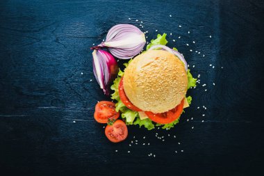 Peynir, et, domates ve soğan ve otlar ile hamburger. Ahşap arka plan üzerinde. Üstten Görünüm. Boş alan.